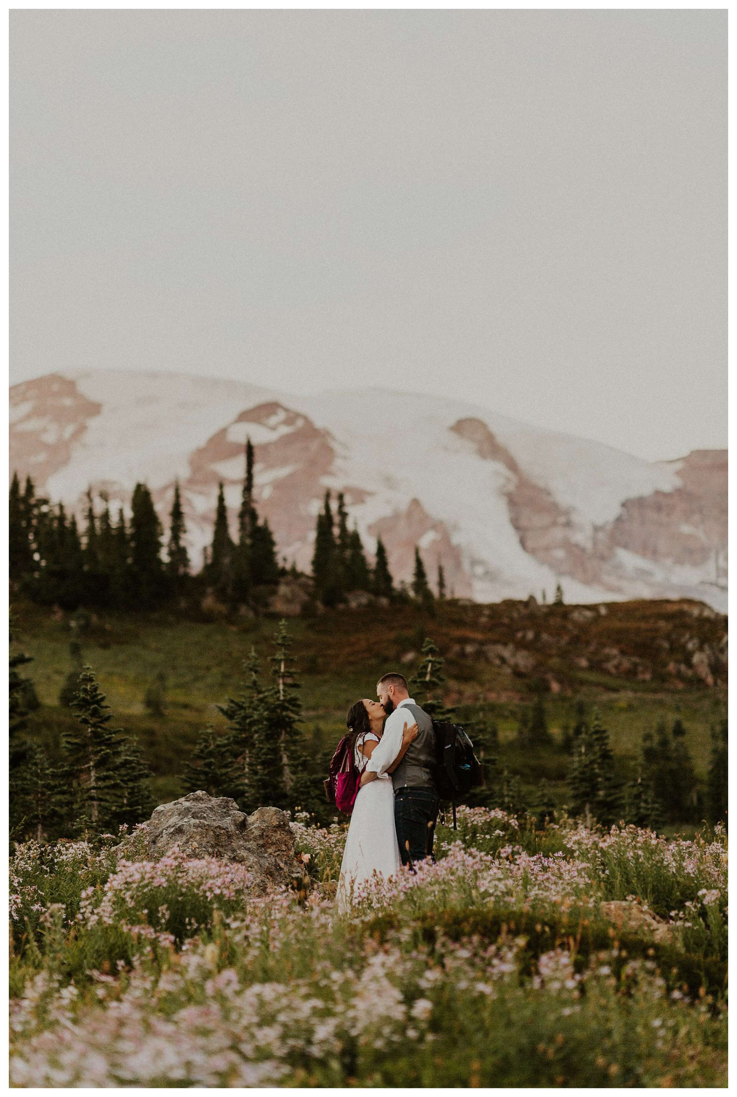 couple standing in meadows in front of mountain 